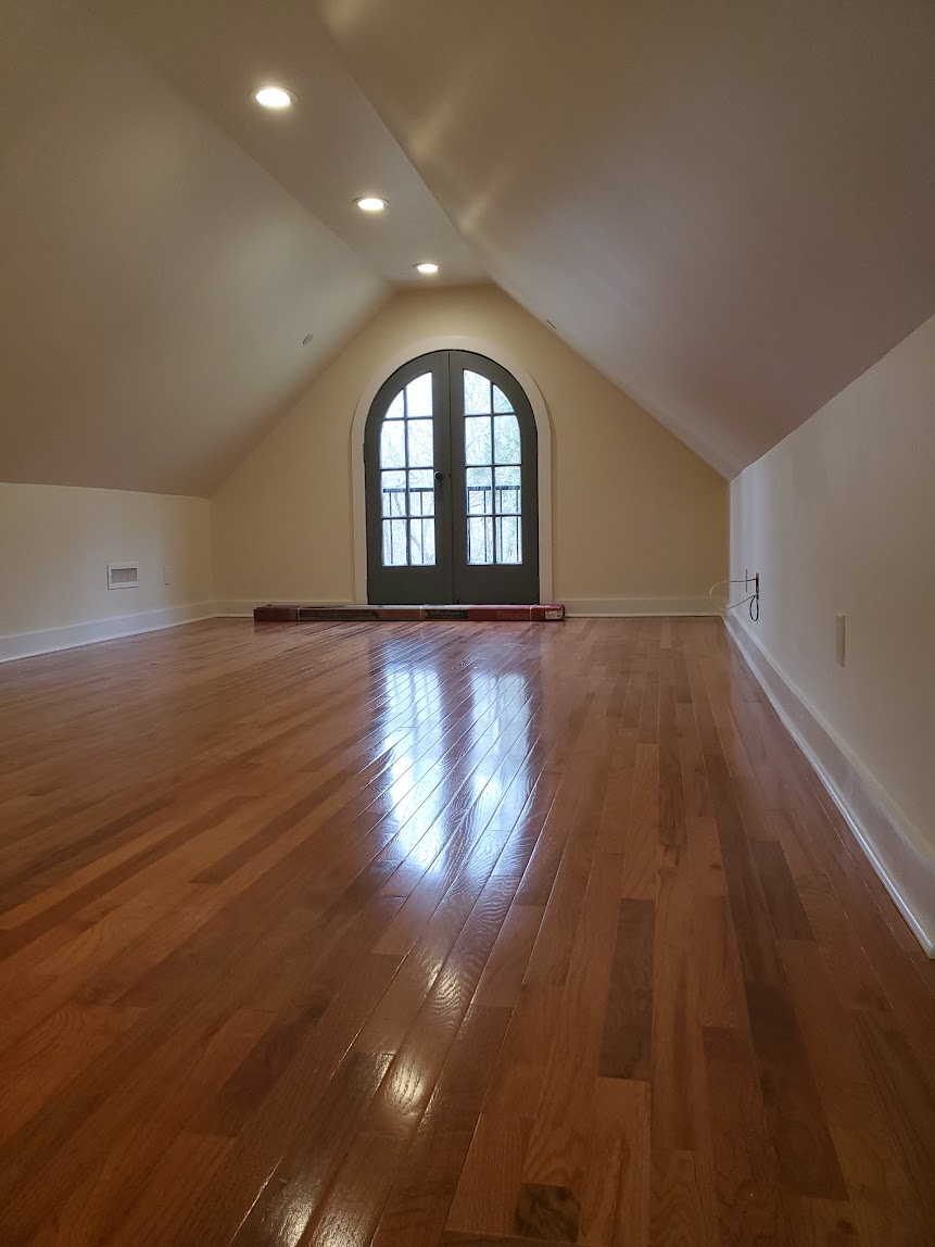 Easton attic conversion with a sloped ceiling, wood floor, recessed lights, and arched double door